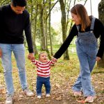 A joyful family enjoys a walk under lush green trees in the park.