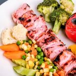grilled meat with green vegetable and red chili on white ceramic plate